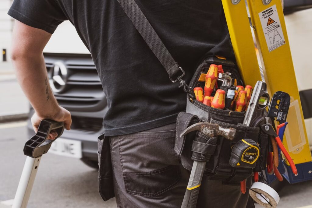 HVAC service technician carrying tools and a ladder